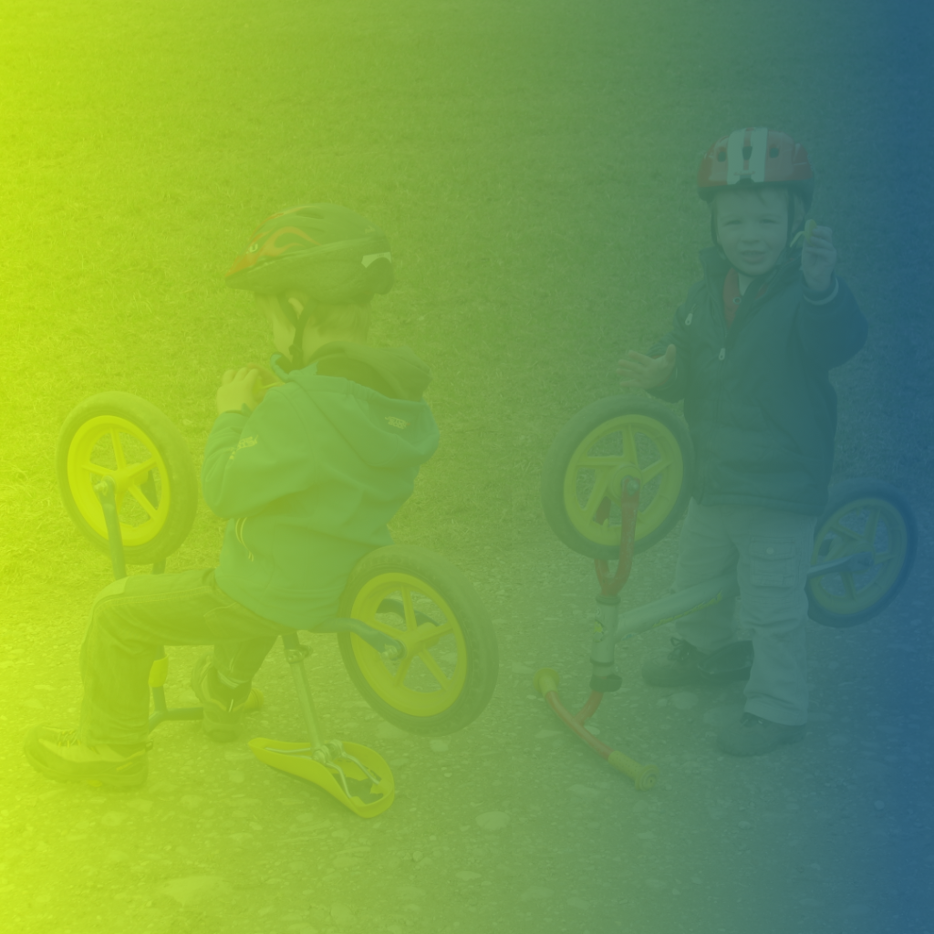 Zwei Brüder sitzen auf umgedrehten Kinderfahrrädern. Lernen am Modell: Der Kleine macht es dem Großen nach.